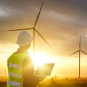energy-sector-worker-looking-at-a-wind-farm-at-sunset